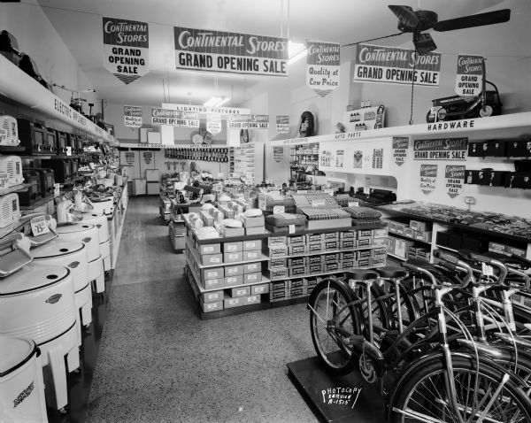 Continental Store grand opening sale, 6 North Street. Interior view showing counters and merchandise, washing machines, bicycles, auto parts and cash register.
