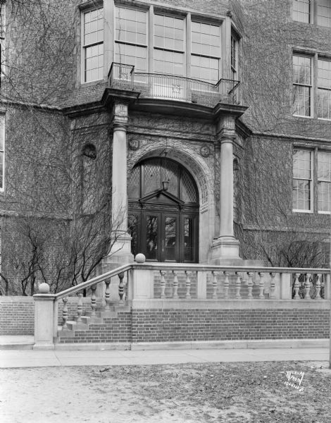 View of the Central High School entrance arch at 214 Wisconsin Avenue. Ivy is growing around the entrance, and is obscuring the carved letters of "High School" above the arch.