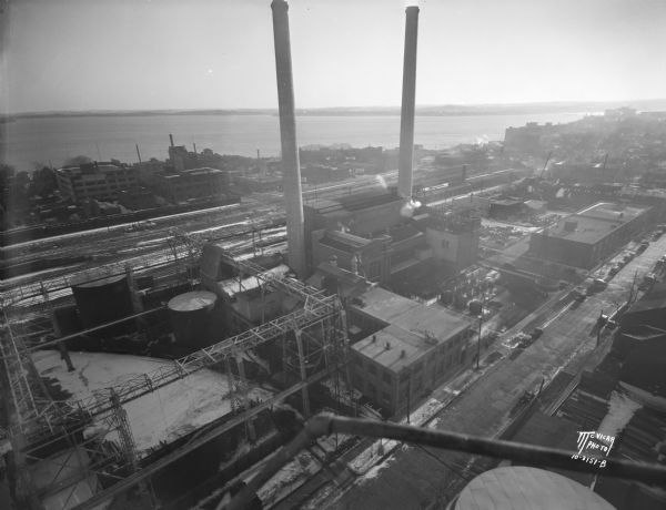 Aerial view of Madison industrial district taken from the top of the Madison Gas and Electric Co. gas tank looking south west down the 600 and 700 blocks of East Main Street, toward Lake Monona. "The dual personality of Madison is typified in this photograph, which, in the foreground, shows the heart of the city's industrial section, and in the background, tranquil Lake Monona."