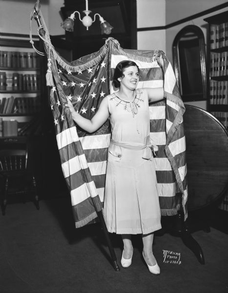 Queen contestant at the Disabled American Veterans Ball, standing and posing with a flag.
