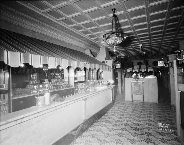 Interior view of the Tavern Cafe at 212 State Street. Along the left is a striped awing over the counter and soda fountain.