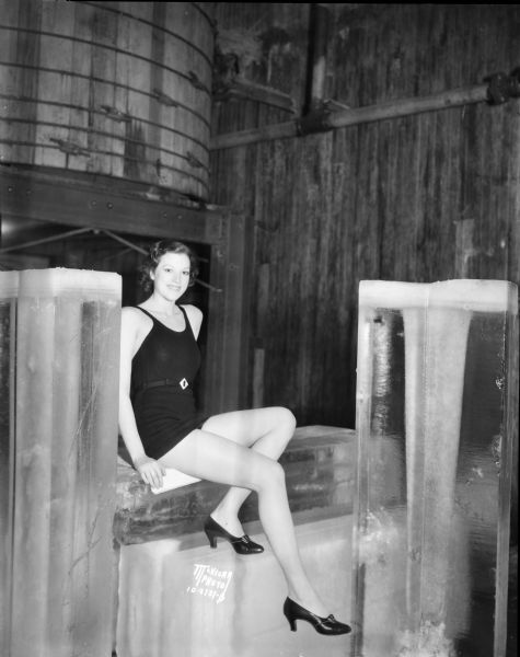Thora Thorbergson, "mermaid" from Iceland, a Fanchon & Marco showgirl, posing in a swimming suit on a block of ice.