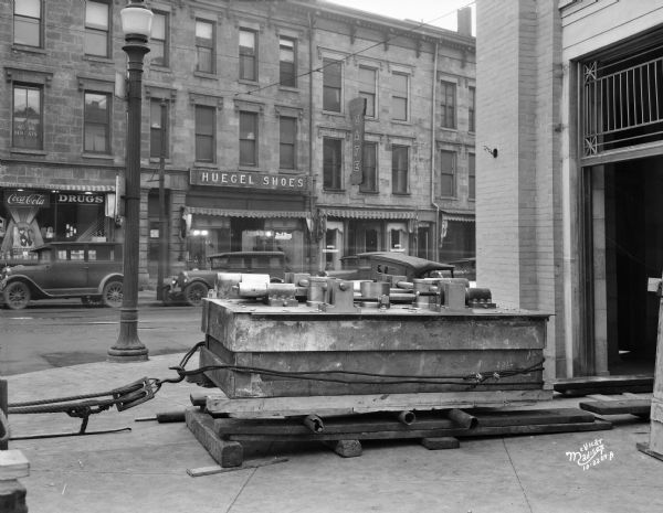 New vault door being delivered to Capital City Bank at 101 King Street. In the background across the street is the Dettloff Drug Store at 102 King Street, the Huegel Shoe Store at 104 King Street, and Boese's Cafe at 106 King Street.