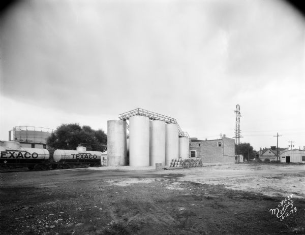 The Texas Company USA (Texaco) office building and storage tanks bulk plant at 919 E. Main Street. The view is from the east, with Texaco railroad tank cars on the left. Text on prints reads: "Capitol Oil. Co."