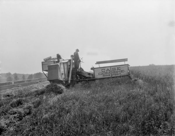 Man cutting and threshing with Case 9-foot combine, at University of Wisconsin Hill Farm.
