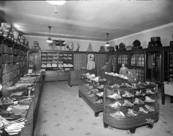 Slightly elevated view of the interior of the College Shop. Two male clerks are behind the counter of the shop at 720 State Street.