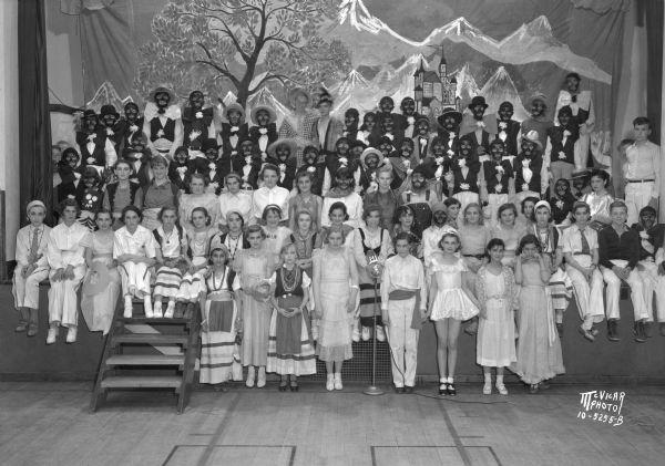 Group portrait of a large group of children in costume, some in blackface, on the stage at Franklin School. 305 W. Lakeside Street.