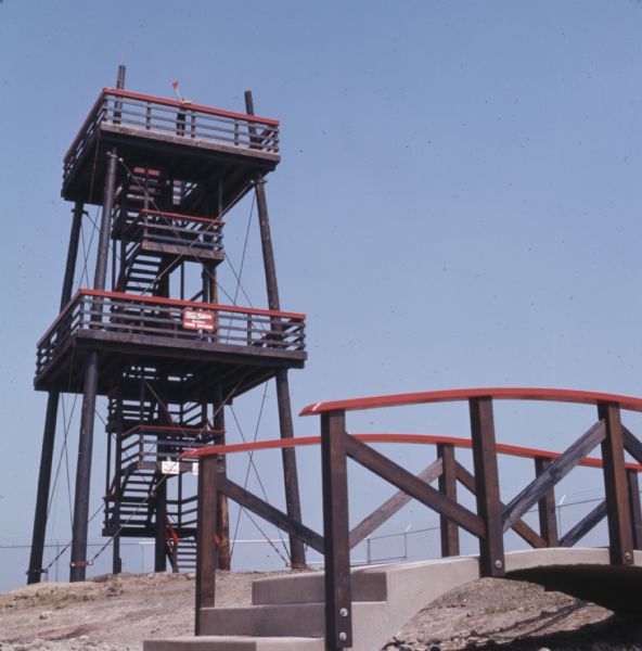 A young boy is waving his red plastic firefighter hat while standing at the top of the five-story fire lookout tower at the Hall of Flame Fire Museum.