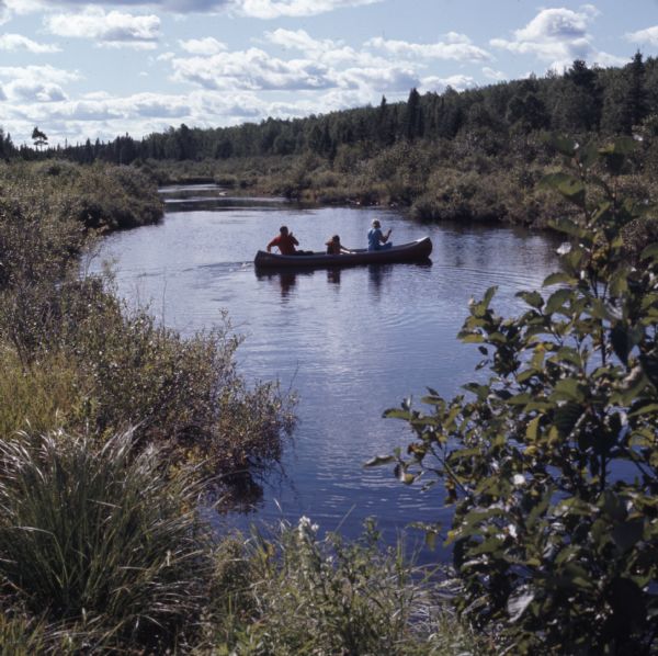 Three people paddling down the Brule River in a canoe.