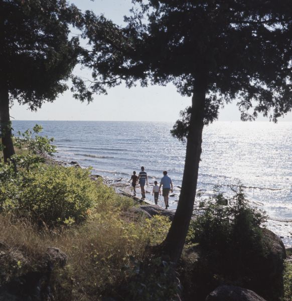 View down slope towards a family walking along the shore of Lake Michigan at Gordon Lodge.