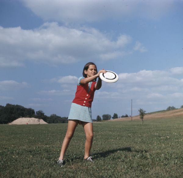 A young girl in a field is catching a Frisbee.