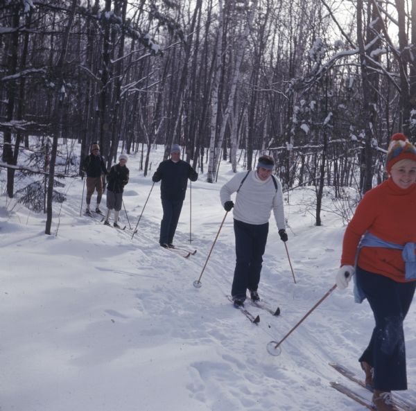A group of people are cross country skiing through the woods.