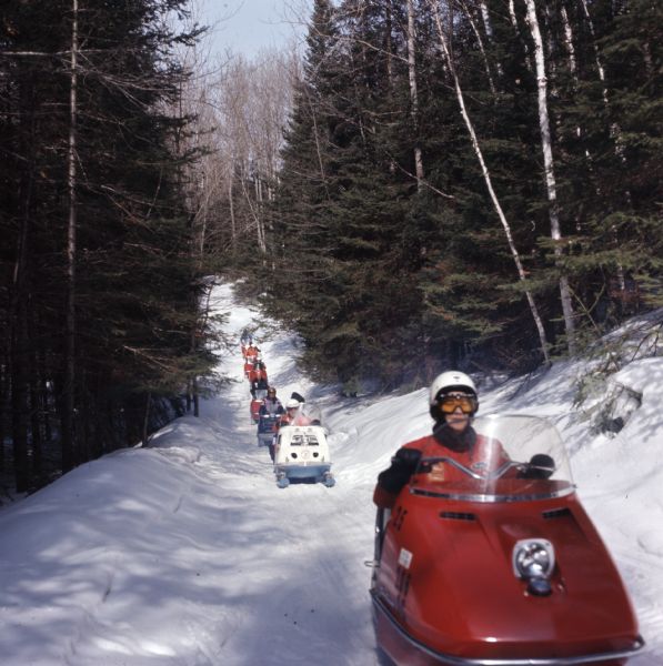 View towards a group of people riding snowmobiles up a path through the Nicolet National Forest.