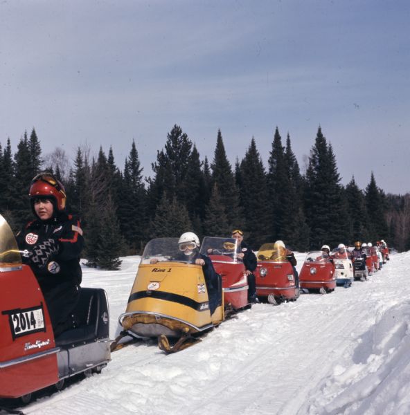 A line of people snowmobiling up a path through Nicolet National Forest.