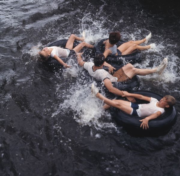 Overhead view of a group of young people sitting in inner tubes splashing the water with their feet in the Apple River.