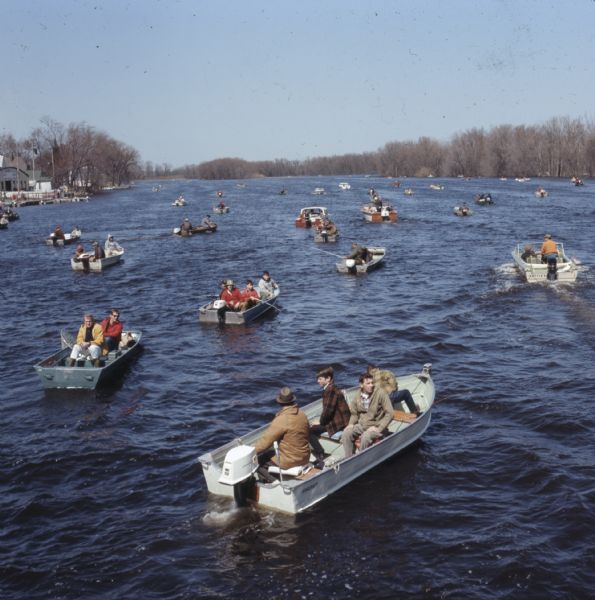 Elevated view of many groups of people sitting in motorboats fishing on the Wolf River.