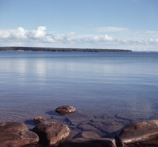 View from rocky shoreline of towards one of the Apostle Islands across the water.