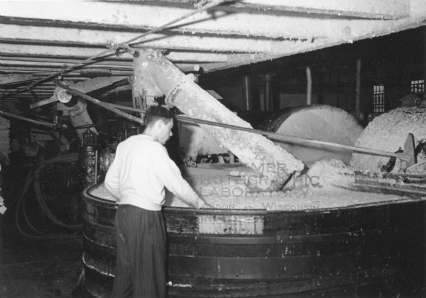 A young man is working at a pulp vat in a paper mill.