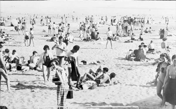 Slightly elevated view of a crowd of mostly young men and women enjoying a sunny day at South Shore Beach.