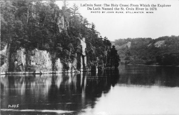 A retouched photographic postcard view across water towards rock formations along the St. Croix River in Interstate State Park. The caption reads: "LaCroix Sant (The Holy Cross) From Which the Explorer Du Luth Named the St Croix River in 1679." Although frequently noted, this rock formation did not play a role in the naming of the river.  