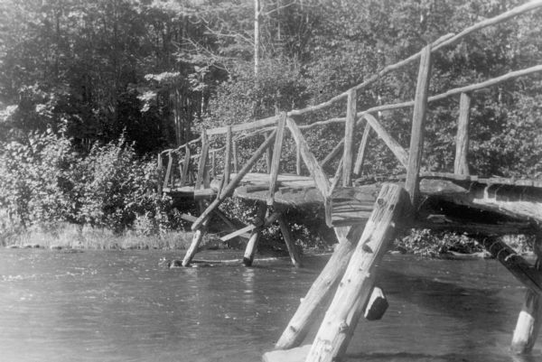 A rustic log footbridge crosses the Bois Brule River at the Superior Brule Club.