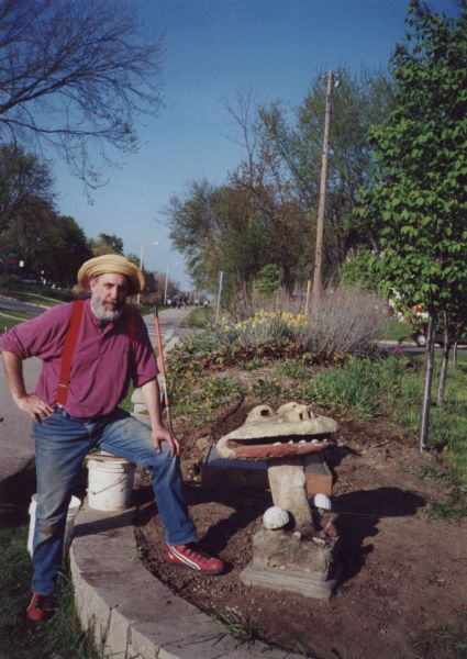 Lou Host-Jablonski, AIA architect, standing by the "Smiling Mushroom" and a new concrete foundation that he poured for the "Blue Dragon Urn." Both sculptures are from Sid Boyum's backyard and were relocated to the public green space on the bike path at Atwood Avenue and Dunning Street. The freshly installed square foundation is behind the "Smiling Mushroom." Daffodils are in bloom in the background with other spring bulbs.

The sculpture relocation and public installation was a community-based, volunteer project to preserve Boyum's larger outdoor work to public parks, landscaped areas and private residences throughout the Atwood-Schenk neighborhood.