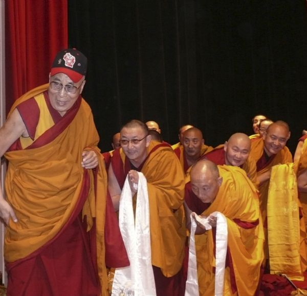 His Holiness, the Dalai Lama at the Masonic Temple, with entourage of monks and wearing a Bucky Badger cap given to him during introductions earlier that morning.