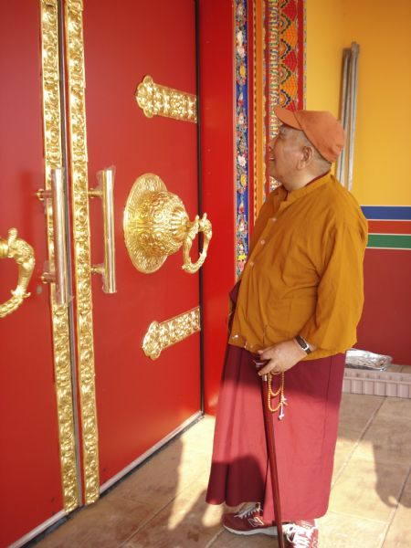 Abbott, Geshe L Sopa, inspecting art objects on the doors of the Deer Park Buddhist Center Temple.