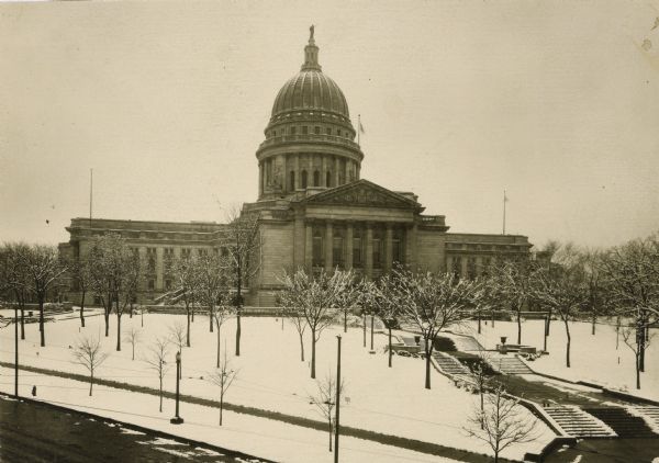 Elevated view of the west wing of the Wisconsin State Capitol building. A view of the fourth capitol with snow flocked trees and snow-covered lawn and sidewalk.