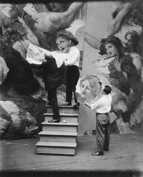 Three men working on the "Resources of Wisconsin" mural. 

The "Resources of Wisconsin mural" painting is located 250 feet above the ground level of the Wisconsin State Capitol. It covers a space in the eye of the dome that is equal to the size of the rotunda floor within the railing... 34 feet in diameter.

To accommodate to the bowl shaped ceiling space, Edwin Blashfield, the artist, built a bowl, 7 feet in diameter. He then he painted smaller cutouts of various parts of the painting such as heads or arms which he arranged rather like a jigsaw puzzle until he got the effect he wanted. Then he worked it out full sized from this model.