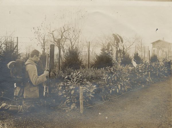 German soldier kneeling on the ground at a mass grave site to say a prayer in honor of his fallen comrades. 