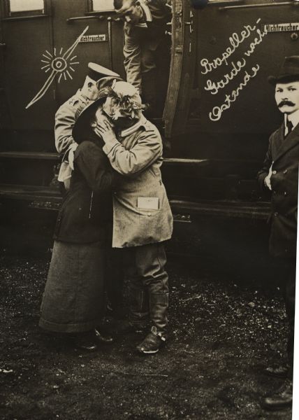 A German soldier is kissing a woman before boarding a train.