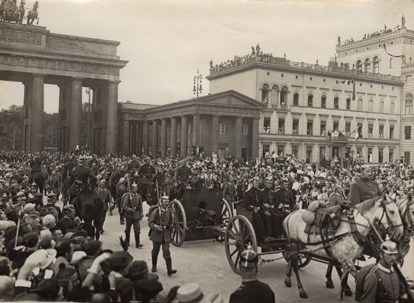 Elevated view of crowd watching soldiers with captured Belgian guns coming through the Brandenburg Gate.