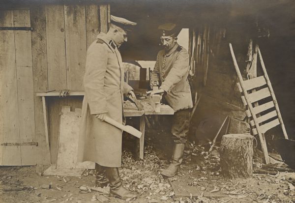Two German soldiers shaping axe handles at a field carpentry shop.