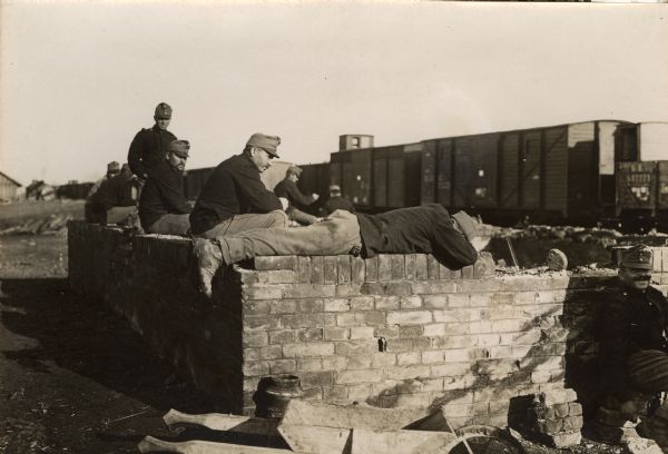 Austrian soldiers waiting along near railroad tracks in the ruins of a Serbian train station.