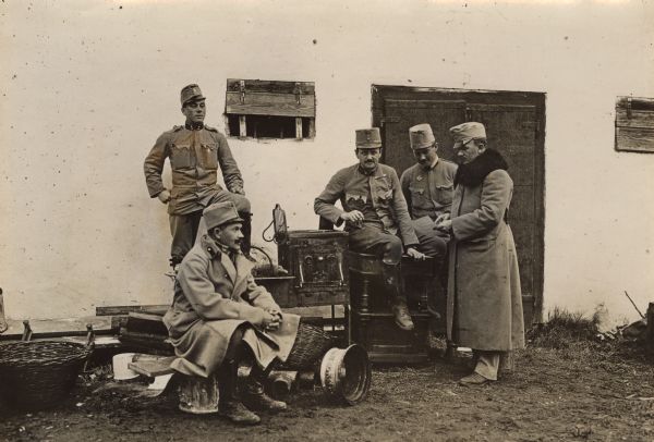 A group of Austrian officers are gathered in front of a building on a Serbian farmstead