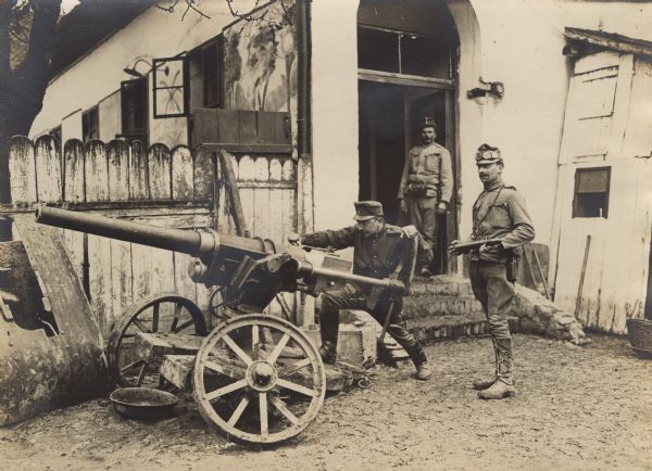 Three Austrian soldiers with a cannon to be mounted on an Austrian river monitor on Danube River during World War I. 
