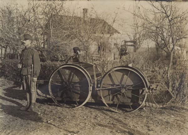 Two Austrian soldiers in front of a piece of agricultural equipment.