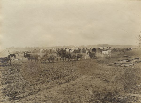 A large group of wagons are carrying weapons and supplies for soldiers on the battlefield. 