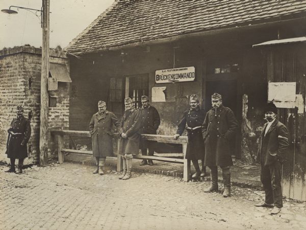 A group of soldiers are standing in front of a building with a sign that reads: "Brückenkommando." (Bridge Command).