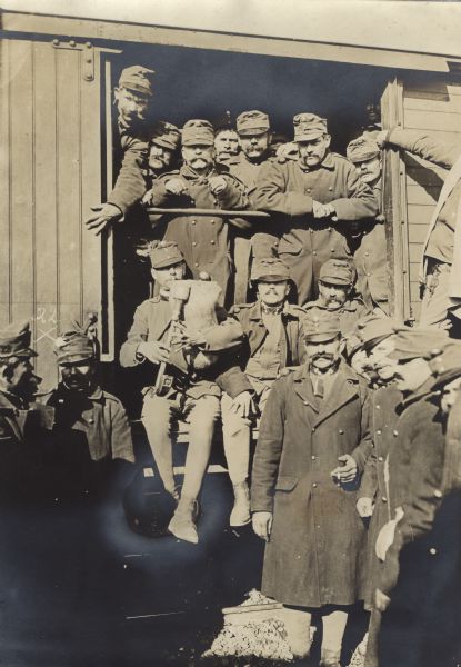 Austrian soldiers from a Croatian "Landsturm" reservist unit posing in and around an open doorway of a railroad car during World War I. One of the men is playing a bagpipe. 