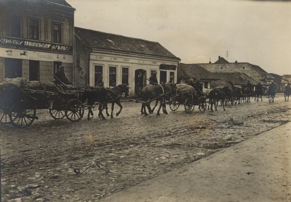 Line of wagons moving up a street with provisions on their way to the front in World War I.