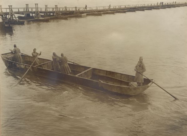 Bosnian soldiers rowing a pontoon section while building a floating bridge across the Sava River in Serbia during World War I.