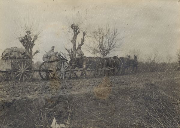 Supply column of soldiers on horseback and on wagons trudging through the rain and mud in World War I. 