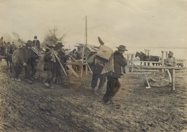 Soldiers and civilians carrying supplies for repairing bad roads in enemy territory during World War I. 