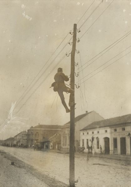A soldier is doing repair work on a telephone pole in Serbia during World War I. 