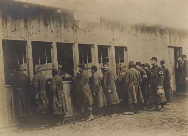 Prisoners in the Zossen camp are lining up before the kitchen as they wait for their meals. 