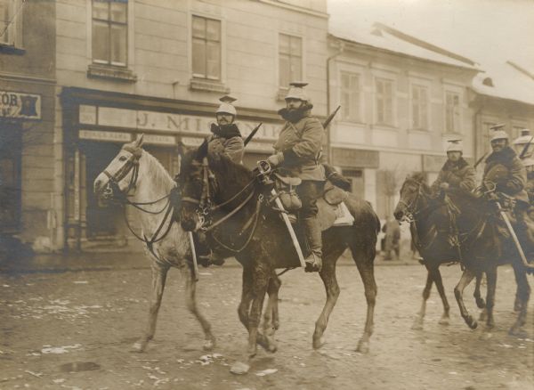 The Austrian Uhlan cavalry patrol is crossing through a city. 