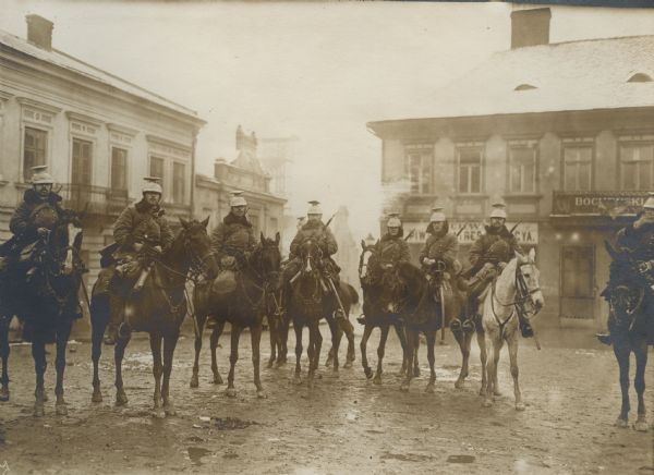 Austrian Uhlans in Galicia posing for the camera in a muddy town square.
