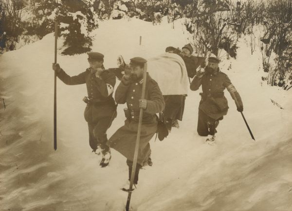 German medics in Galicia carrying a wounded Austrian soldier on a litter through deep snow.